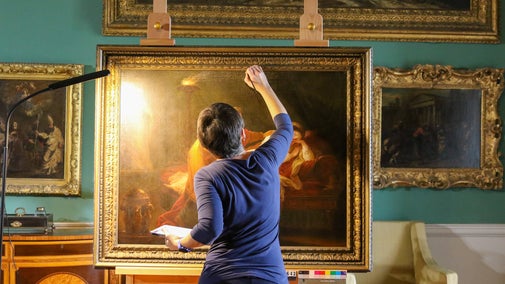Conservator April Johnson applies touch up paint to the fine oil painting 'Penelope and Euriclea' by Angelica Kauffman displayed inside the picture gallery, Stourhead, Wiltshire